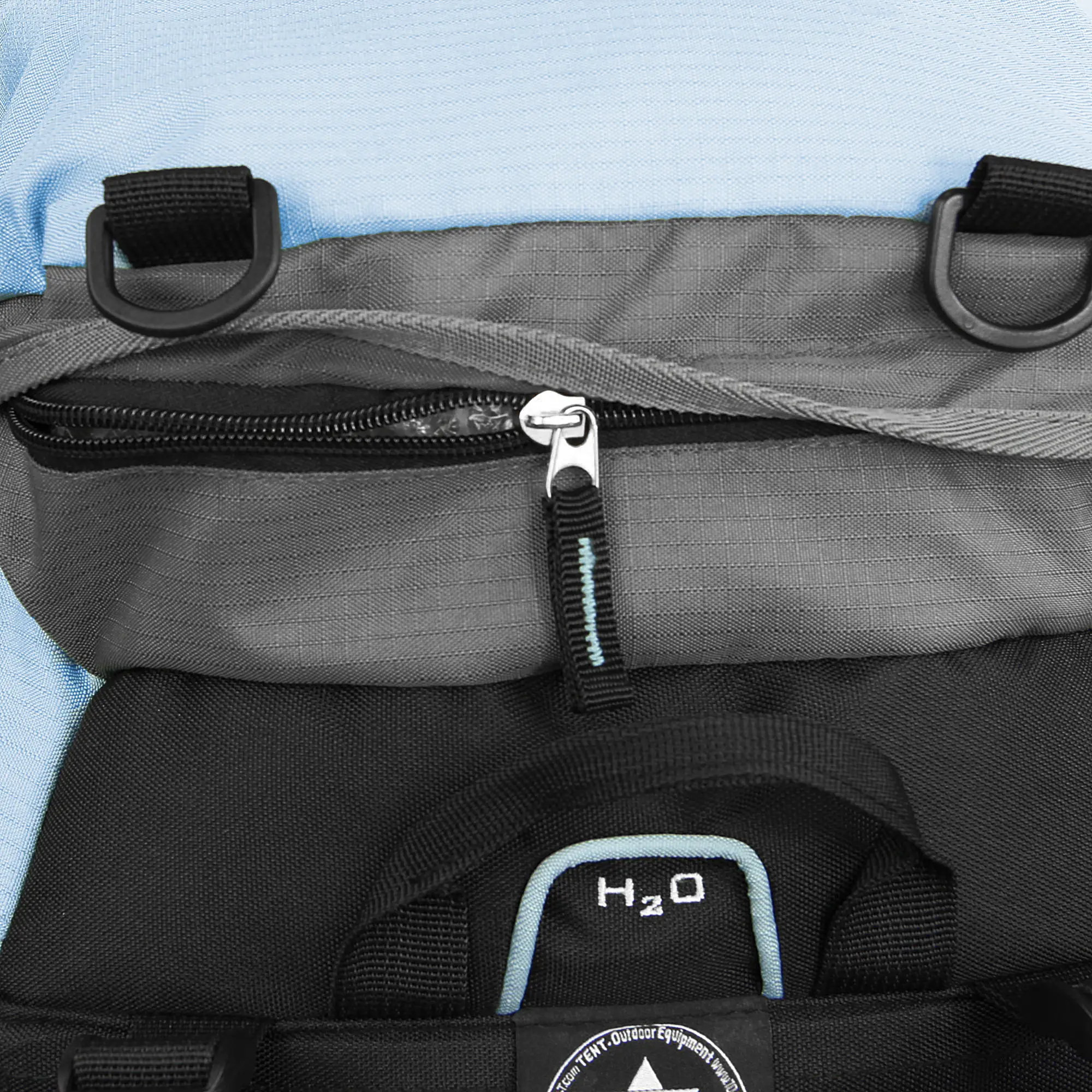 A close-up of a backpack with a blue section, gray top compartment with a zipper, and a black lower section featuring an H2O logo, all made of durable fabric.